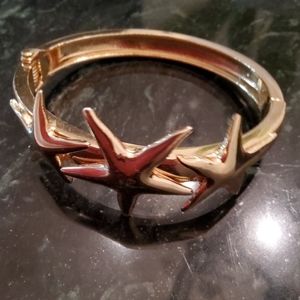 Faux gold tone hinged bracelet with stars